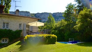 Una casa con piscina, un patio con mesa y sillas, y vistas a la montaña.