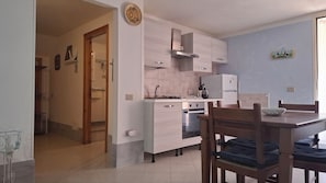 A modern kitchen with light wood cabinets, a built-in oven, and a dining area with a wooden table and chairs. - Apartment " Sa Casaritza" 850 meters from the beach (La Caletta, Siniscola)