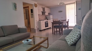 A living room with a sofa, a coffee table, and a dining area with a table and chairs. - Apartment " Sa Casaritza" 850 meters from the beach (La Caletta, Siniscola)