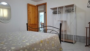 A bedroom with a bed, a wooden door, a wardrobe, and a mirror.