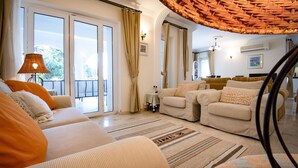 Amplia sala de estar con un conjunto de sofás, un comedor y un balcón con vistas.