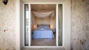 Un dormitorio con cama, mesita de noche, lámpara y dosel.