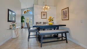 A dining area with a table set for four, a bench, and a chandelier.