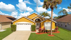 A residential house with a garage, a well-maintained lawn, and a palm tree.