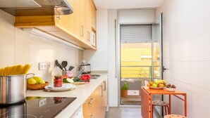 Una cocina compacta con armarios de madera, un horno de acero inoxidable y una pequeña mesa de comedor con taburetes.