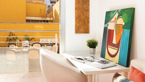 Una habitación moderna con un escritorio blanco, un cuadro abstracto colorido y vistas a un edificio amarillo.