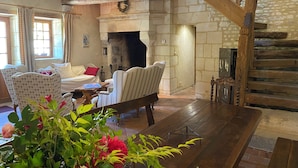 Un salón acogedor con chimenea de piedra, vigas de madera y asientos cómodos.