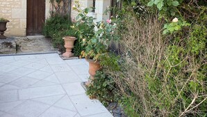 Un edificio de piedra con un patio empedrado, una puerta de madera y una planta en maceta.