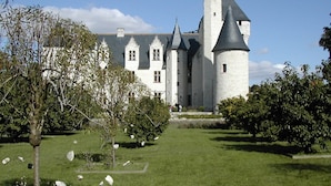Un gran castillo blanco con múltiples torres y un césped bien cuidado al frente.