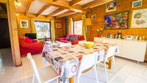 A cozy cabin interior with a dining table, chairs, a sofa, and a TV.