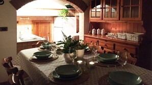 Een eetruimte met een tafel voor vier personen, een houten kast met glazen deuren en een raam dat voor natuurlijk licht zorgt.
