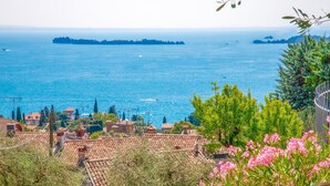Eine Küstenstadt mit Terrakotta-Dächern, Blick auf das Meer und eine entfernte Insel.