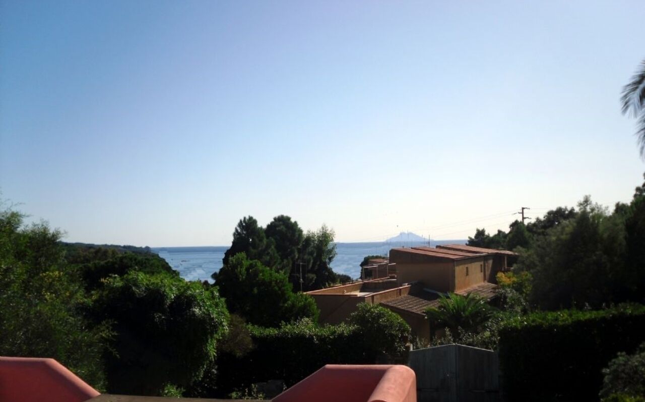 A coastal view with buildings, trees, and a clear sky.