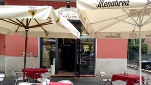 An outdoor café with tables and chairs, umbrellas, and a building entrance. - HAPPY HOME BOLOGNA Cozy, quiet, Close to CITY CENTER and EXHIBITION, AC, WiFi (Bologna)