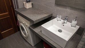 A modern bathroom with a grey countertop, a white sink, and a washing machine. - HAPPY HOME BOLOGNA Cozy, quiet, Close to CITY CENTER and EXHIBITION, AC, WiFi (Bologna)