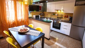 A compact kitchen with a dining area, featuring a microwave, sink, stove, and a refrigerator. - HAPPY HOME BOLOGNA Cozy, quiet, Close to CITY CENTER and EXHIBITION, AC, WiFi (Bologna)