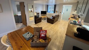 Een moderne keuken met een eethoek, een woonkamer met een bank, en een keukeneiland met een mand vol snacks.