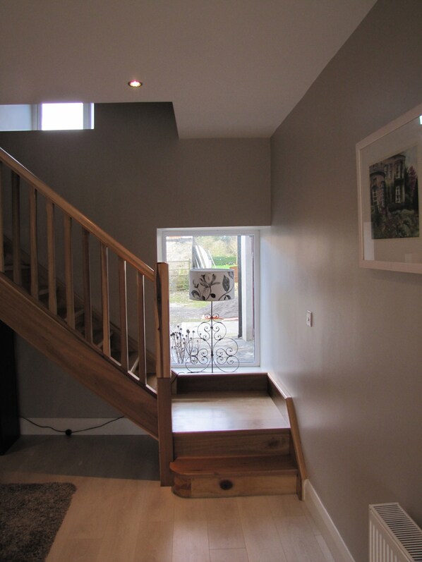A staircase with wooden railings leading to a landing with a window. - 3 bedroom, sleeps 6, beautiful Village in the centre of Ireland (Multyfarnham)
