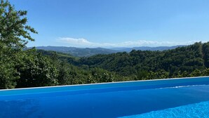 A clear blue infinity pool overlooking a mountainous landscape.