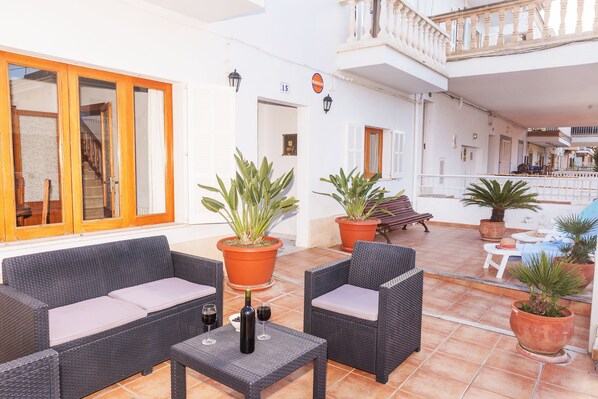 A spacious outdoor area with wicker furniture, potted plants, and a staircase leading to an upper level. - Can Biel, cosy house located 100 metres from the beach (Can Picafort)