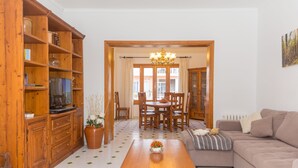 A living room with a wooden cabinet, a television, a dining table with chairs, a sofa, and a chandelier. - Can Biel, cosy  house located 100 metres from the beach (Can Picafort)