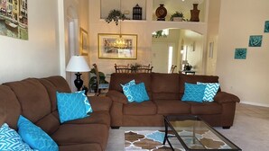 A living room with two brown sofas, a glass coffee table, and patterned rugs. - Lakeview Villa in Kissimmee, pool & hot tub, free pool heat, close to Disney (Kissimmee)
