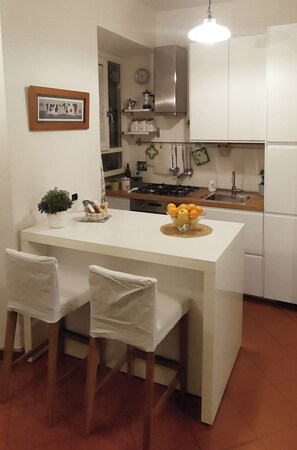 A compact kitchen with a central island, two chairs, a sink, and a stove.