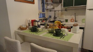Uma cozinha compacta com área de refeições, equipada com eletrodomésticos e utensílios básicos.