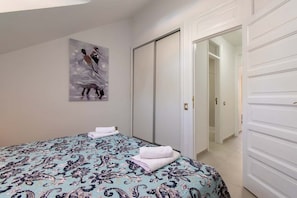 A bedroom with a bed, a painting, and a closet. - Parque Santiago II Duplex (Playa de Las Americas)