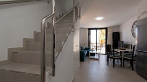 A modern apartment with a staircase, a dining area, and a kitchen.