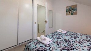 A bedroom with a bed, a wardrobe, a mirror, and a painting on the wall.