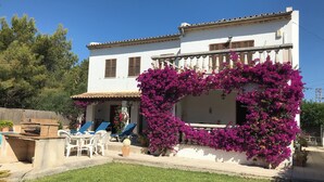 A two-story house with a white facade, a tiled roof, and a balcony with blue chairs. - "Casa Montana" Holiday house for 6 persons with Private Pool (Puerto Pollensa)