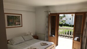 A bedroom with a wooden bed, a nightstand, a framed picture, and an open balcony door. - "Casa Montana" Holiday house for 6 persons with Private Pool (Puerto Pollensa)