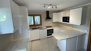 A modern kitchen with white cabinets, a black range hood, a built-in oven, and a marble countertop. - "Casa Montana" Holiday house for 6 persons with Private Pool (Puerto Pollensa)