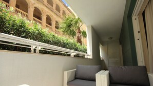 Ein Balkon mit Korbmöbeln und Blick auf ein Gebäude mit Bögen.