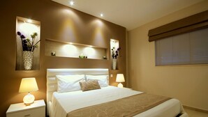 Ein ordentlich eingerichtetes Schlafzimmer mit einem großen Bett, Nachttischen mit Lampen, dekorativen Wandschränken und einem Fenster mit Jalousien.