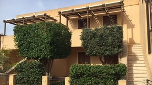 Un edificio con fachada color beige, un espacio al aire libre cubierto y una escalera.