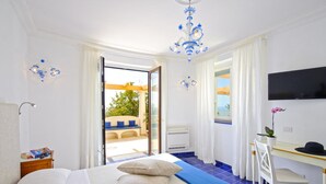 A bedroom with a bed, a desk, a chair, a TV, and a view of the outside. - Il canto delle sirene,  in the heart of Amalfi Coast, parking Property overview (Conca dei Marini)