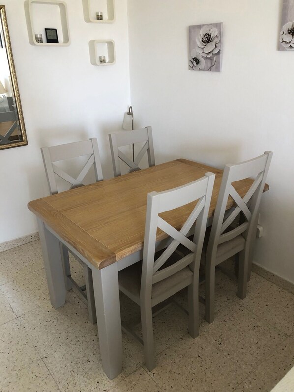 A dining table with four chairs, a wall-mounted light, and a mirror.