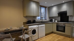 A compact kitchen with a washing machine, a microwave, and a stove. - Recently renovated 2 bedroom annexe with open plan living room and kitchen. (Stoney Middleton)