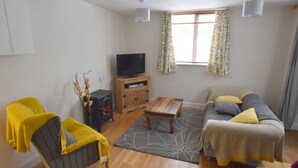 A living room with a sofa, a wooden coffee table, a television on a cabinet, and a fireplace. - Recently renovated 2 bedroom annexe with open plan living room and kitchen. (Stoney Middleton)