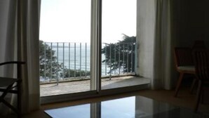 Ein Zimmer mit einer großen Glasschiebetür, die auf einen Balkon mit Meerblick führt.