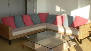 Ein Wohnzimmer mit einem Ecksofa, einem Glastisch und einer Stehlampe.