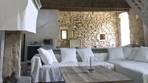 A rustic interior with a stone wall, wooden beams, a white sofa, and a wooden table. - In Uzès, quiet, loft in independent 18th century mill with 15mx3m swimming pool (Uzès)