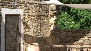 A rustic outdoor seating area with a stone wall, a large terracotta pot, and metal chairs. - In Uzès, quiet, loft in independent 18th century mill with 15mx3m swimming pool (Uzès)