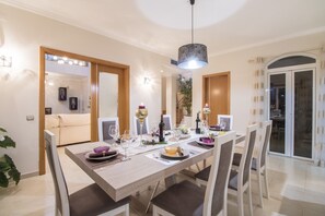 A dining area with a long table, chairs, and a hanging light fixture.