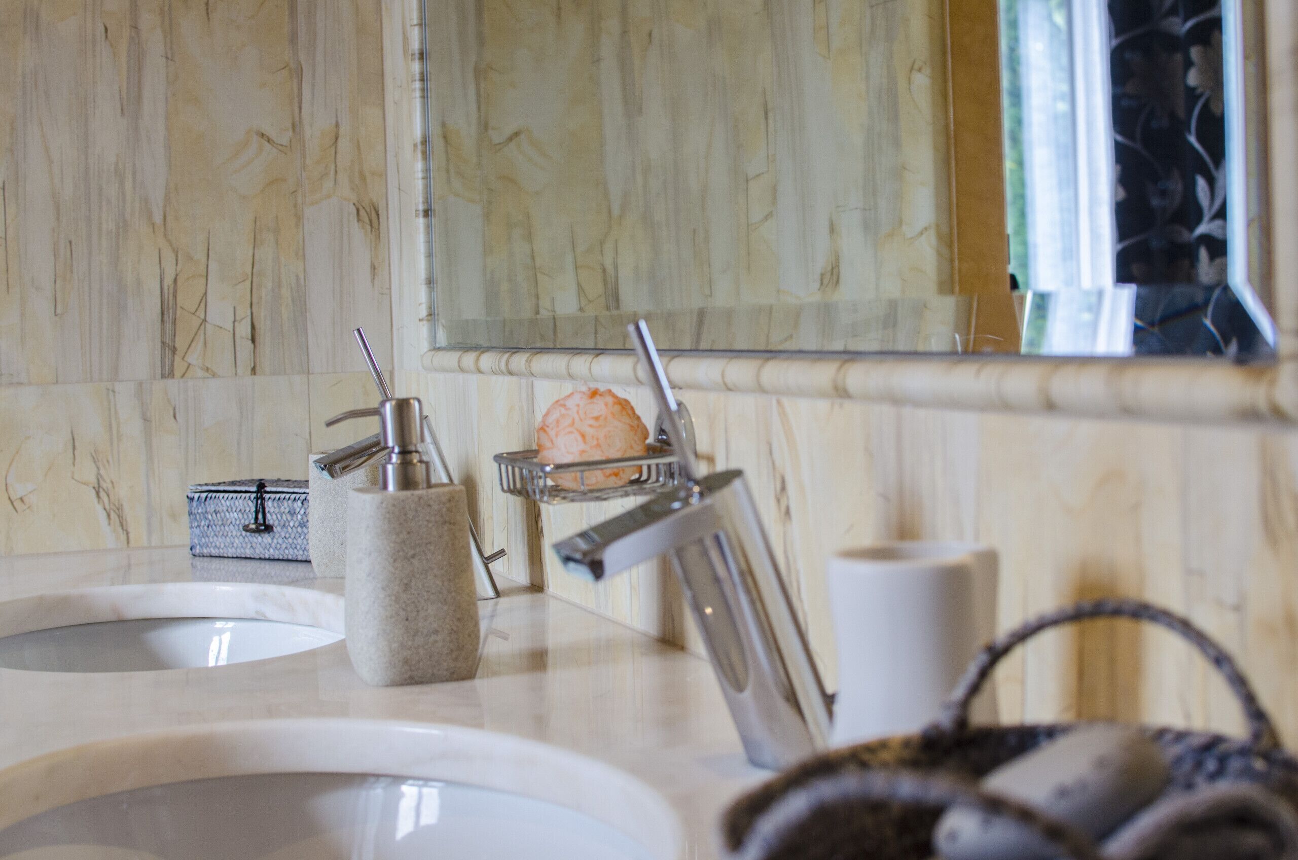 Un bagno con lavabo in marmo, portasciuga asciugamani, saponiera e specchio.