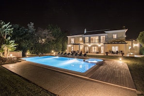 Ein großer Pool mit Liegestühlen und einer gut beleuchteten Terrassenanlage.