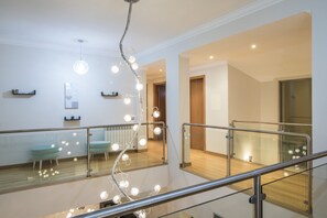 Un intérieur moderne avec une balustrade en verre, un luminaire en forme de spirale et un plancher en bois.