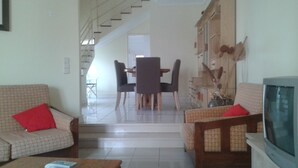 Una sala de estar con sofá, televisión y comedor con mesa y sillas.